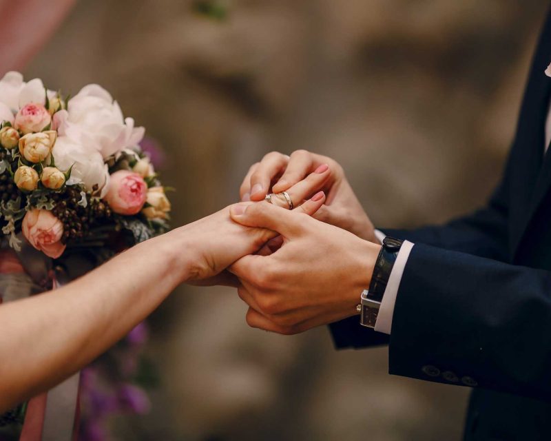 groom putting ring bride s finger